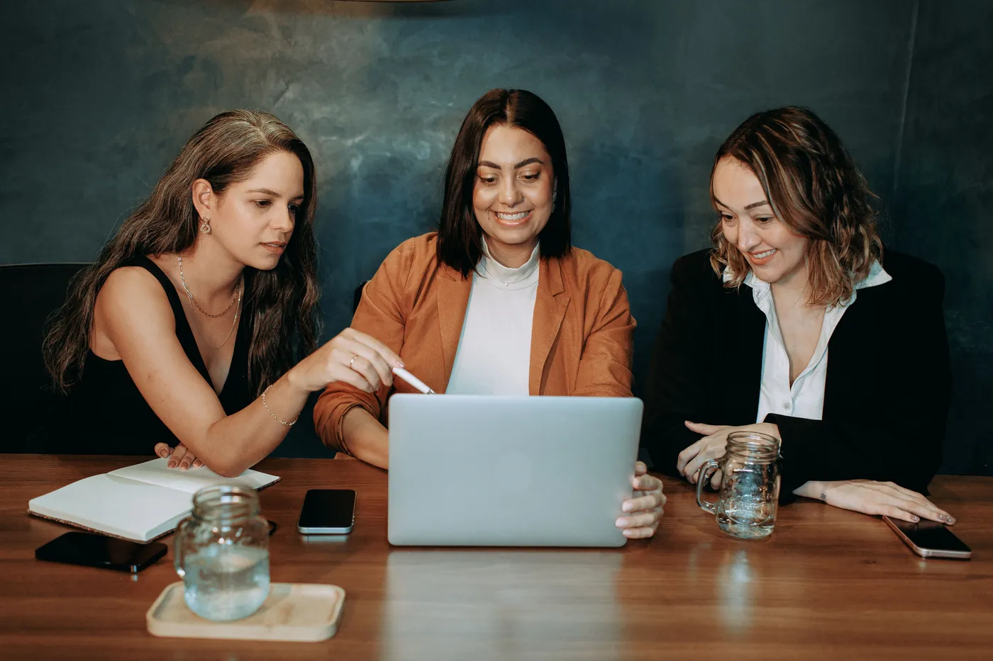 Equipe reunida à mesa, olhando juntas o notebook