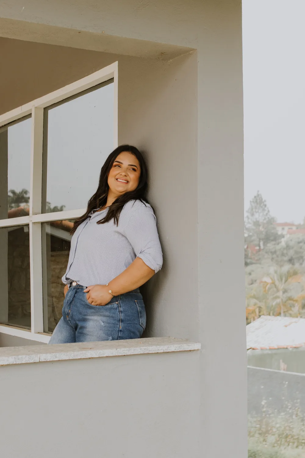 Moradora sorrindo na sacada do prédio