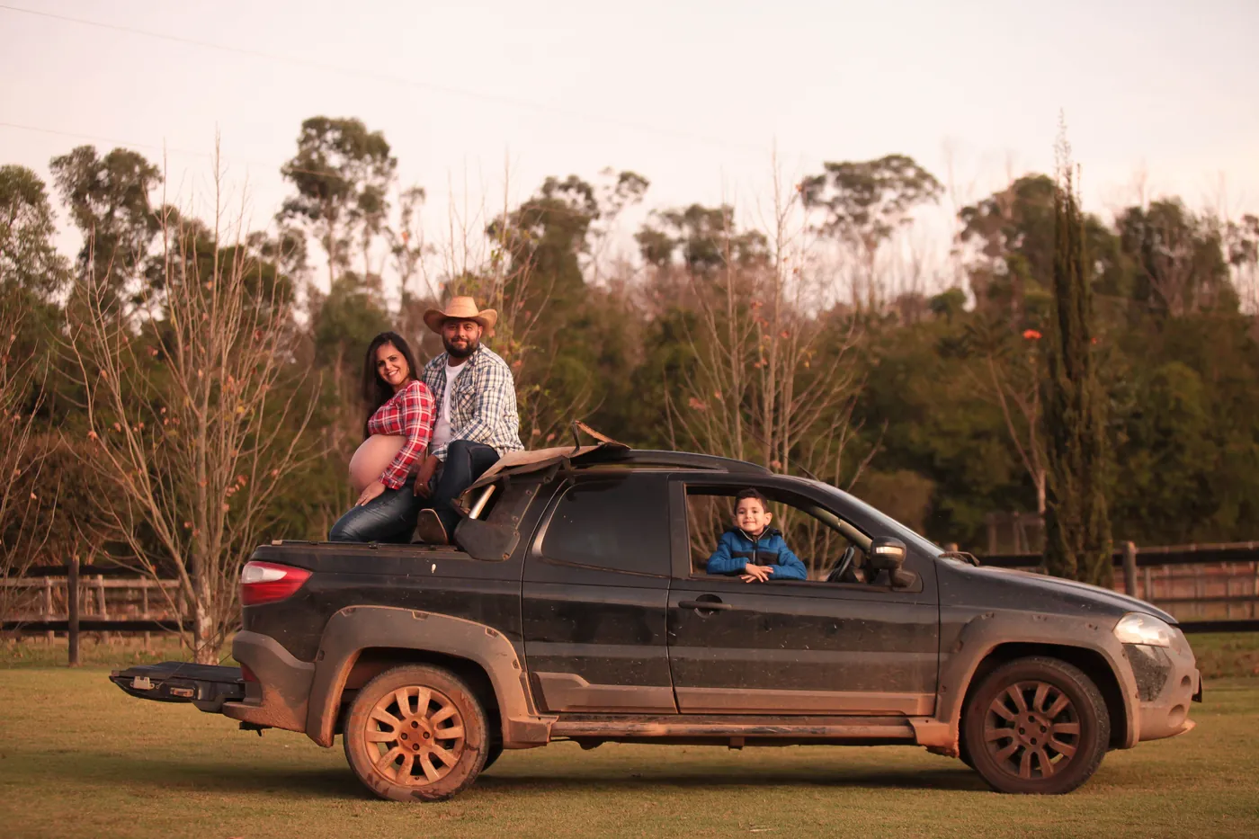 Família com o filho na janela da caminhonete, no campo